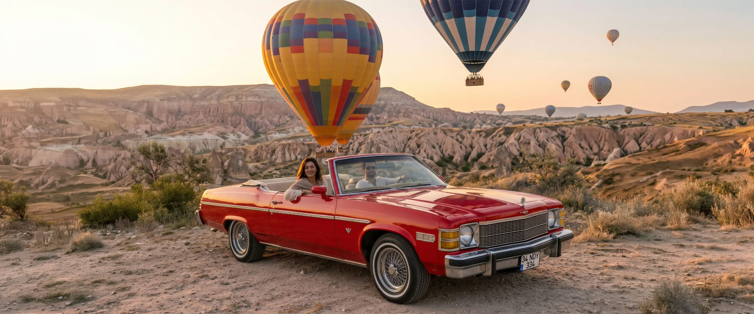 Red 1976 Buick Skylark convertible with hot air balloons at sunrise in Cappadocia
