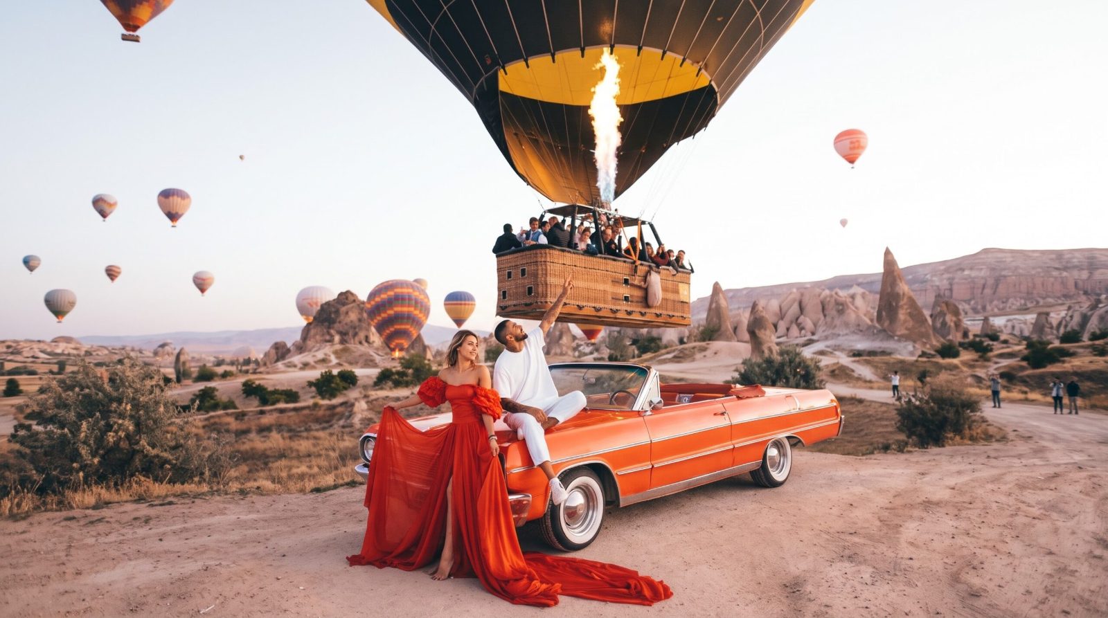 Couple with an orange classic car next to a hot air balloon taking off in Cappadocia